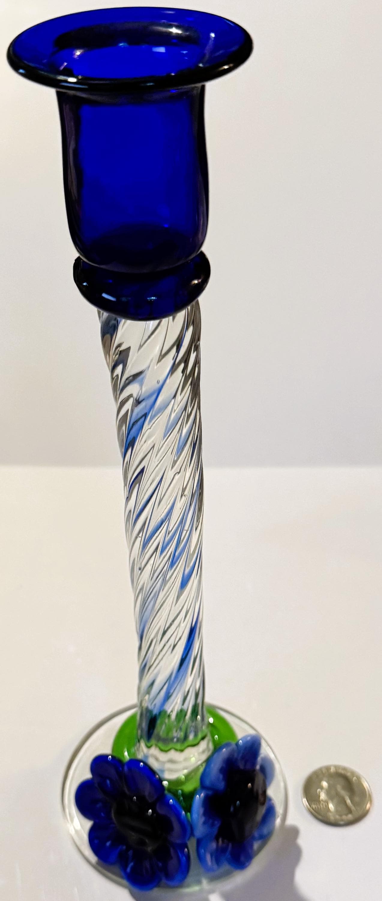 Tall blue art glass candlestick with twisted latticino stem, green base with blue applied flowers, shown next to a quarter fo