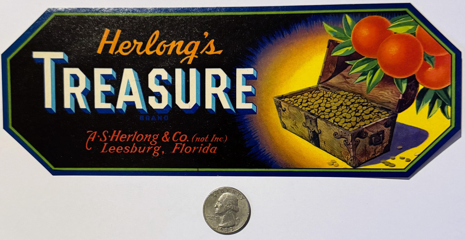 Vintage Herlong's Treasure crate label with pirate chest, oranges, and gold coins, shown with quarter for scale.