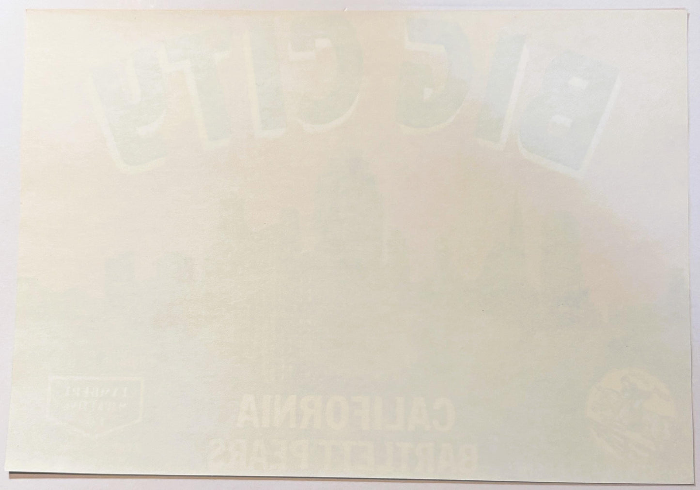 Cream-colored vintage pear crate label with faded cityscape silhouette at top and partially visible text below