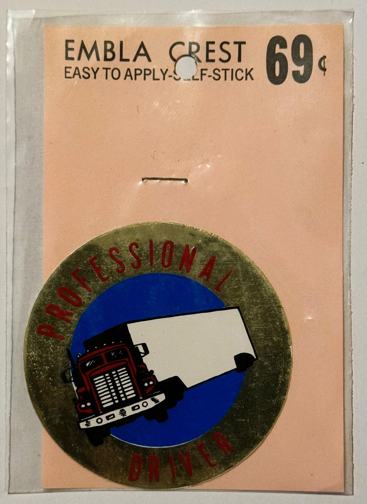 Vintage self-stick emblem crest decal on peach card showing red semi truck on blue circle, priced 69 cents, unopened in plast