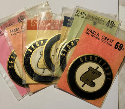 Collection of vintage Embla Crest self-stick decals in pink, orange, and yellow packages, priced 49¢-69¢, fanned display show