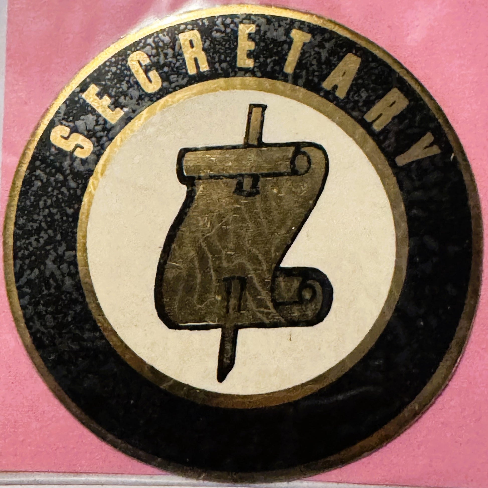 Circular vintage decal with "Secretary" text around dark border and large number 3 on cream center, photographed against pink