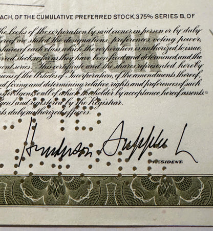 Close-up of signed stock certificate showing cursive signature and "PRESIDENT" label, with decorative border and ornate patte