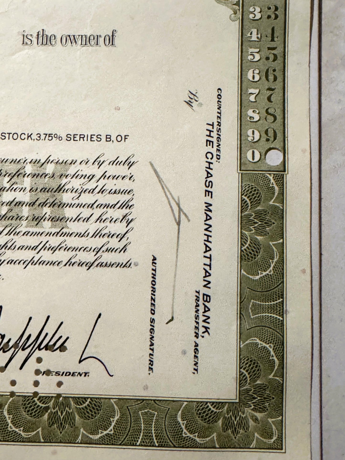 Close-up of vintage stock certificate corner showing ornate green border, numbered scale 3-9, and text reading "is the owner 