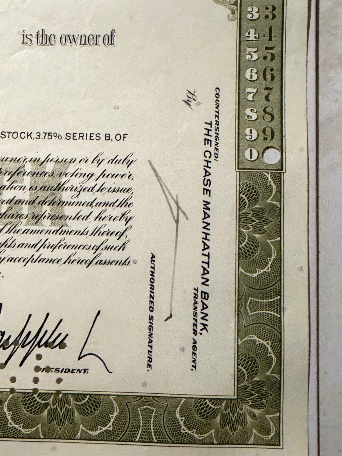 Close-up of vintage stock certificate corner showing ornate green border, numbered scale 3-9, and text reading "is the owner 