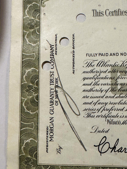 Close-up of vintage stock certificate with ornate border, showing "Morgan Guaranty Trust Company" text, punch holes, handwrit