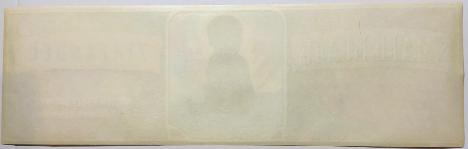 Faded cream-colored vintage fruit crate label with embossed silhouette of person in center, text illegible due to age and fad