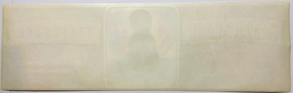 Faded cream-colored vintage fruit crate label with embossed silhouette of person in center, text illegible due to age and fad