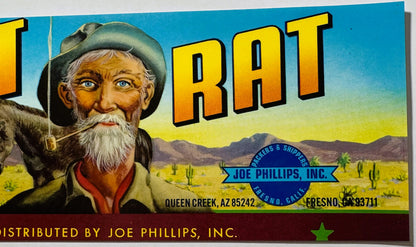 Vintage fruit crate label featuring bearded prospector in cowboy hat against desert landscape with "Desert Rat" text and Joe 