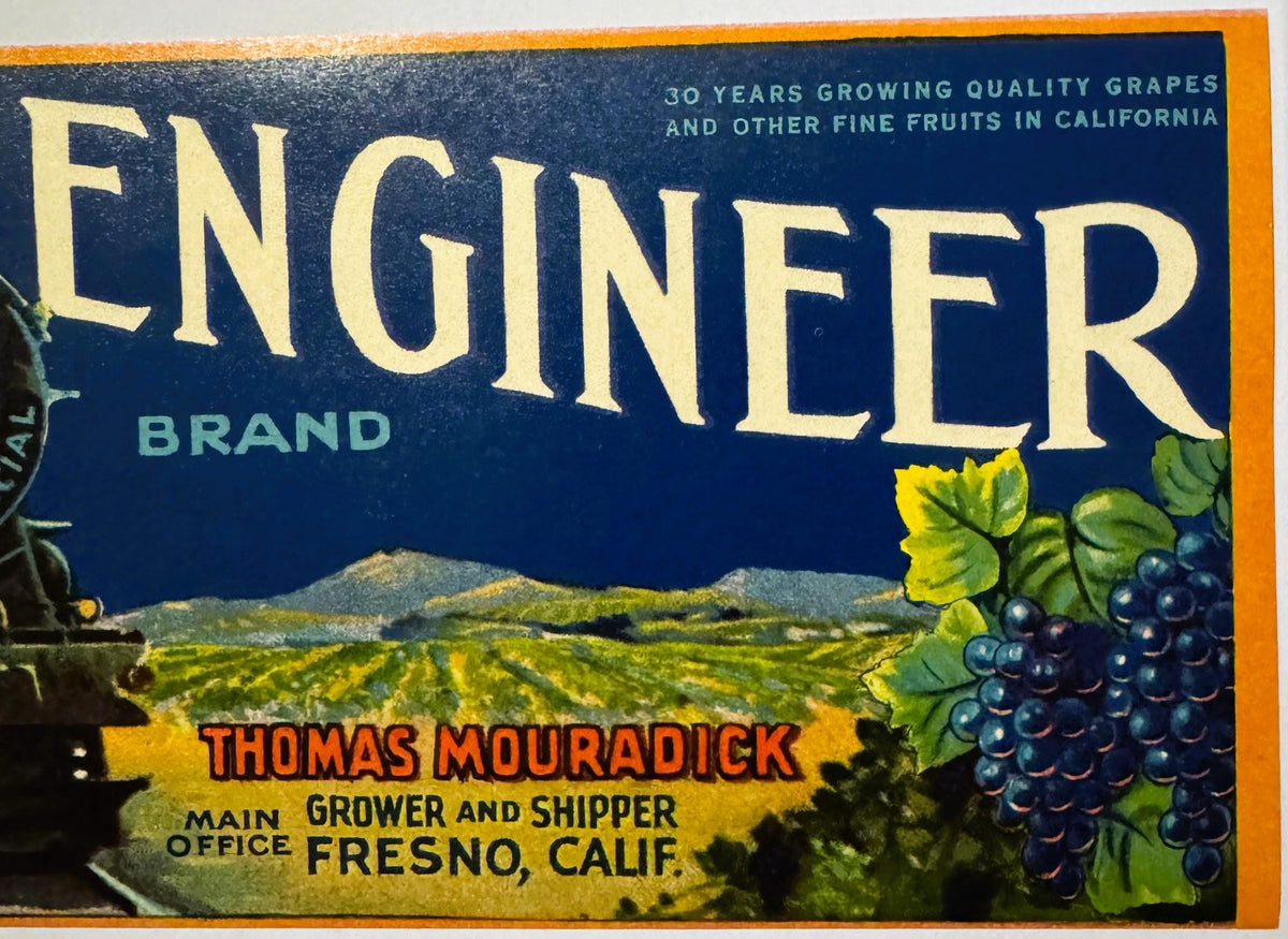 Vintage fruit crate label with "Engeler Brand" in large cream text on dark blue background, featuring dark grapes and vineyar