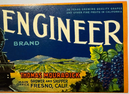 Vintage fruit crate label with "Engeler Brand" in large cream text on dark blue background, featuring dark grapes and vineyar