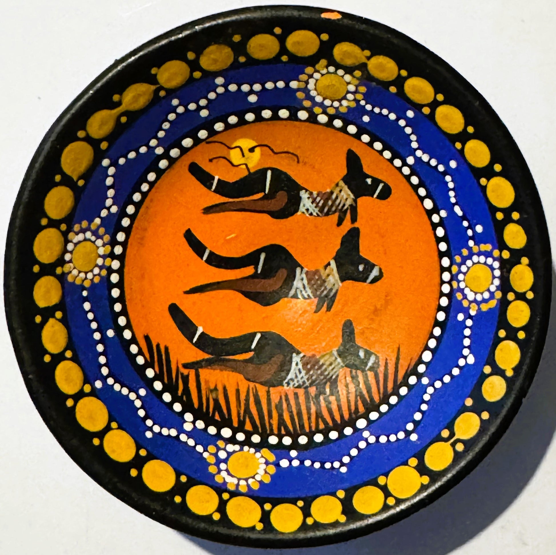 Round black-rimmed ceramic dish with orange center featuring three black kangaroos, surrounded by blue ring with white dotted