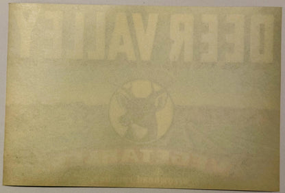 Faded vintage crate label with embossed deer and text, cream-colored paper with age spotting and wear