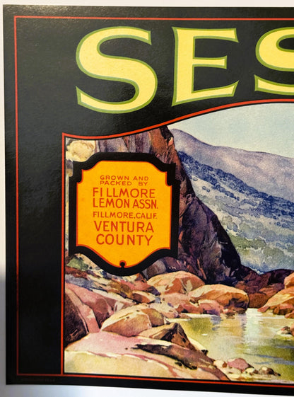 Close-up of the orange shield: GROWN AND PACKED BY FILLMORE LEMON ASSN., FILLMORE, CALIF., VENTURA COUNTY, over the canyon stream and boulders