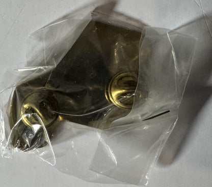 Brass NASCAR pin with two circular holes in clear plastic packaging, displayed flat against white surface