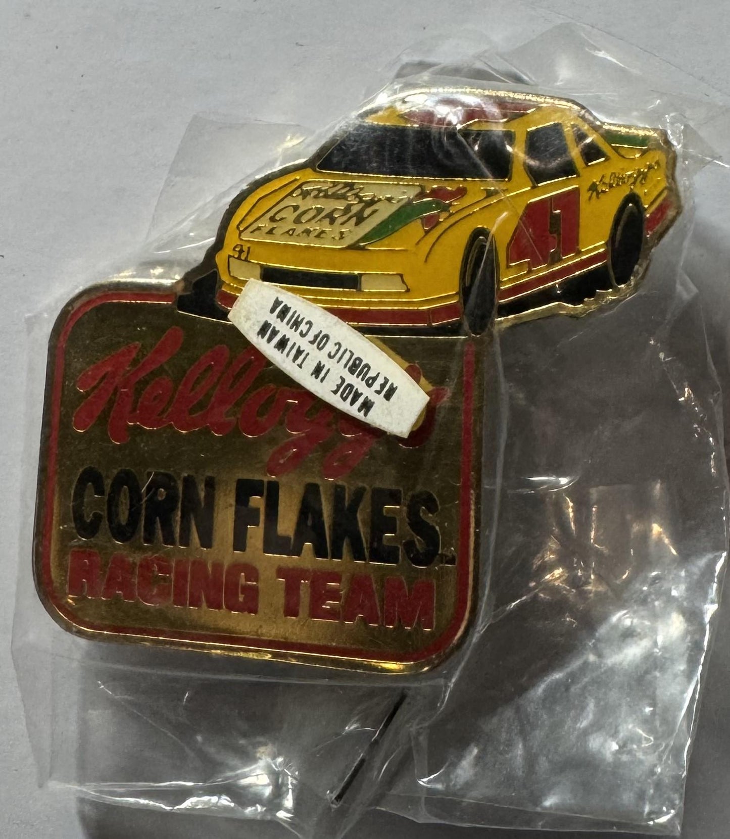 Vintage Kellogg's Corn Flakes Racing Team pin in clear plastic packaging showing yellow #41 NASCAR race car with red and gold