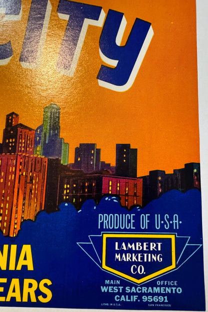 Vintage fruit crate label with orange sky, Art Deco cityscape, blue number 9, and Lambert Marketing Co. text from West Sacram