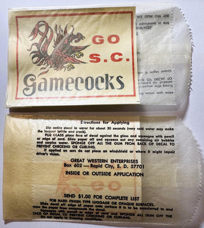 Vintage South Carolina Gamecocks water-transfer decal with gamecock illustration and red text, showing packaging and applicat