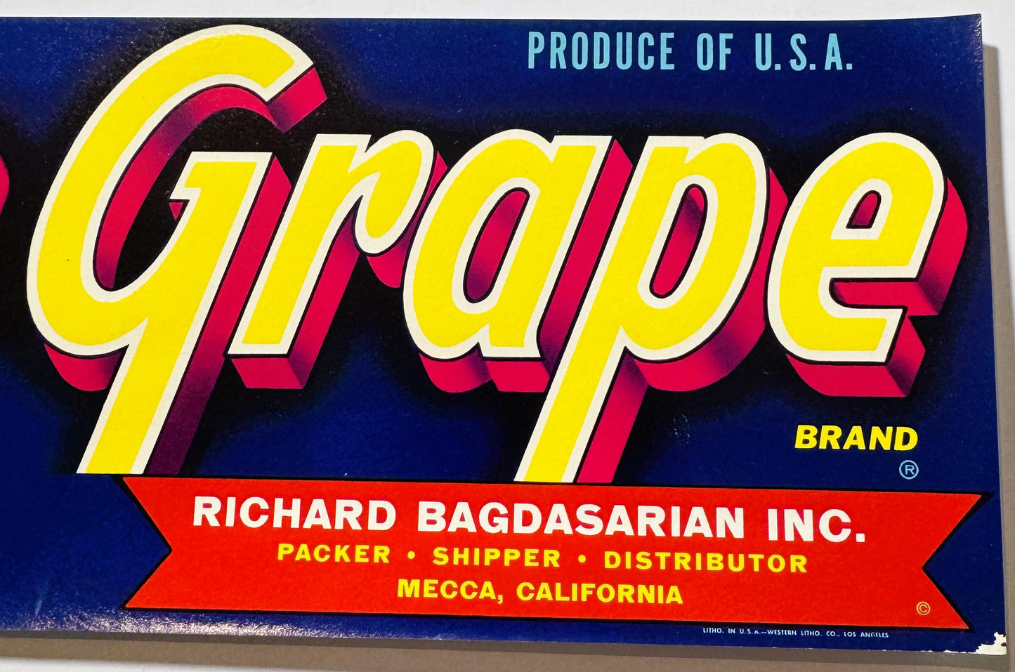 Vintage "Grape" brand fruit crate label with yellow and red 3D lettering on dark blue background, Richard Bagdasarian Inc. co