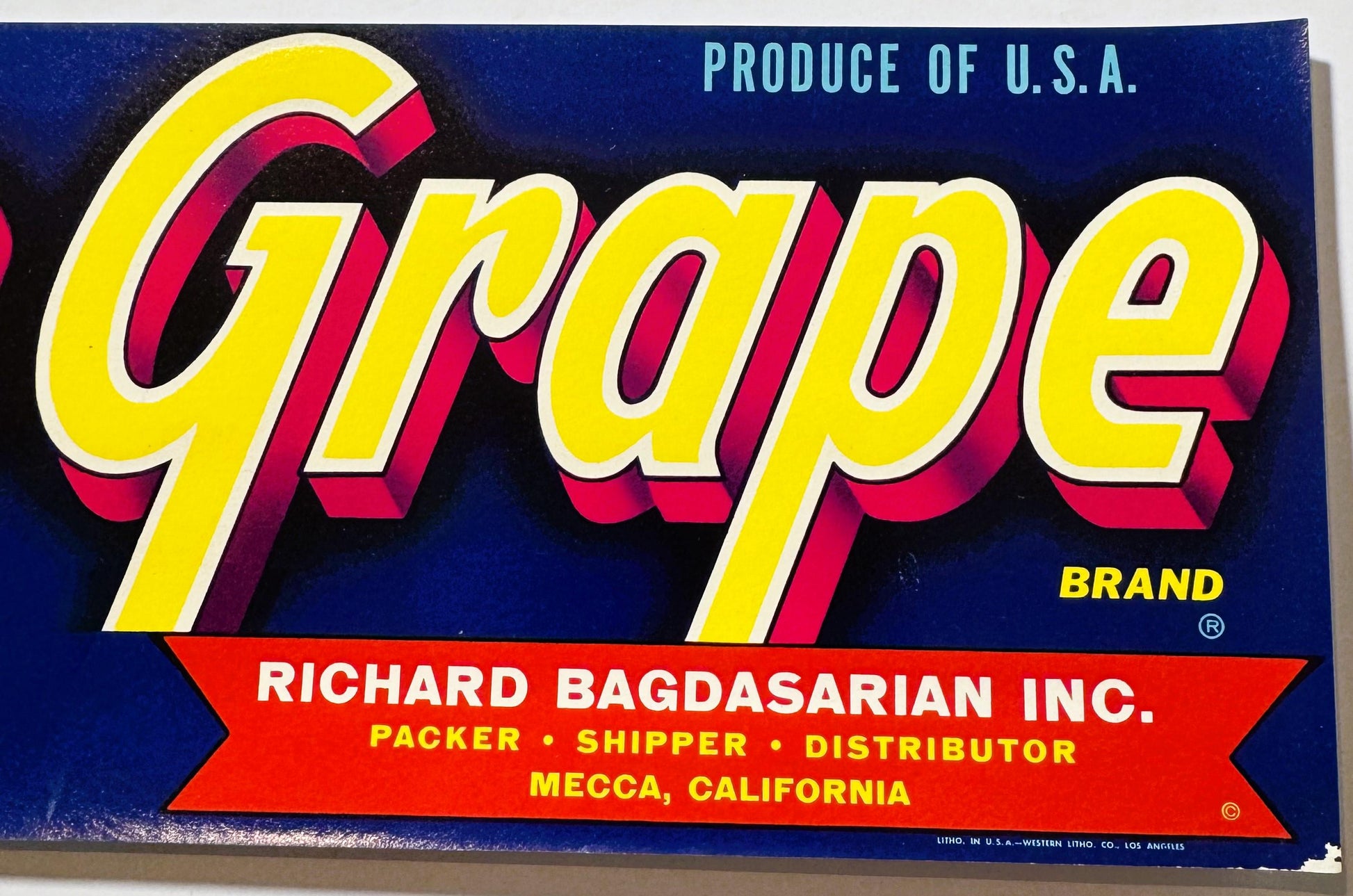 Vintage "Grape" brand fruit crate label with yellow and red 3D lettering on dark blue background, Richard Bagdasarian Inc. co