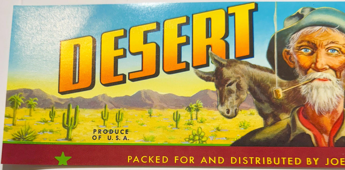 Vintage fruit crate label featuring "Desert" in large yellow letters, bearded prospector with donkey in desert landscape with