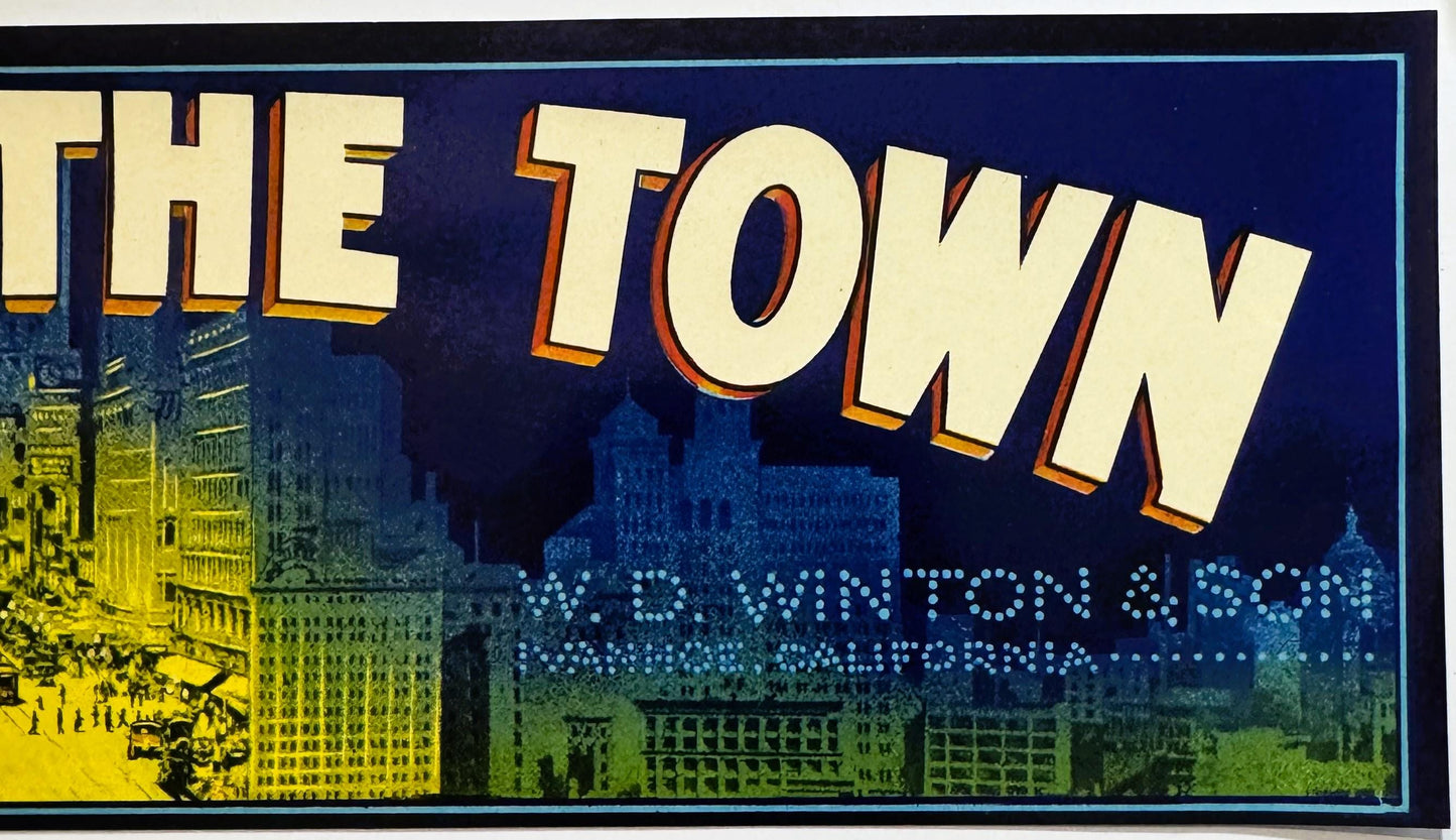 Vintage fruit crate label with "THE TOWN" in large cream and orange letters on dark blue background, cityscape illustration b