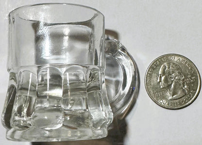 Clear hobnail glass shot or juice glass next to a quarter for scale, showing textured dimpled pattern and handle detail.