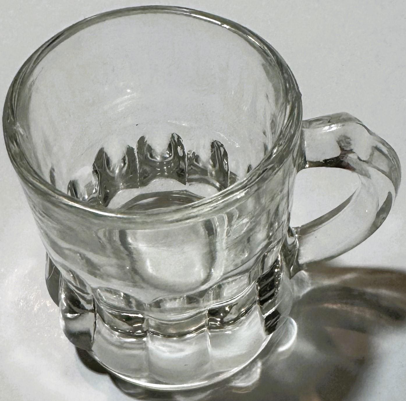 Clear glass hobnail mug with handle shown at angle against white background, displaying textured dimple pattern on body and b