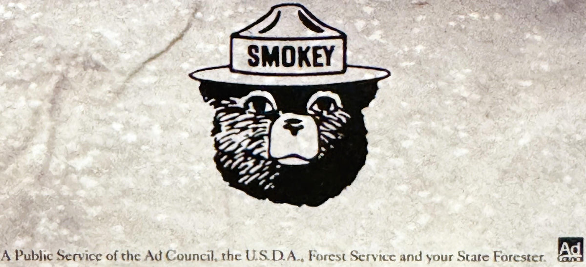 Black and white illustration of Smokey the Bear wearing a ranger hat with "SMOKEY" text, on textured light background with at