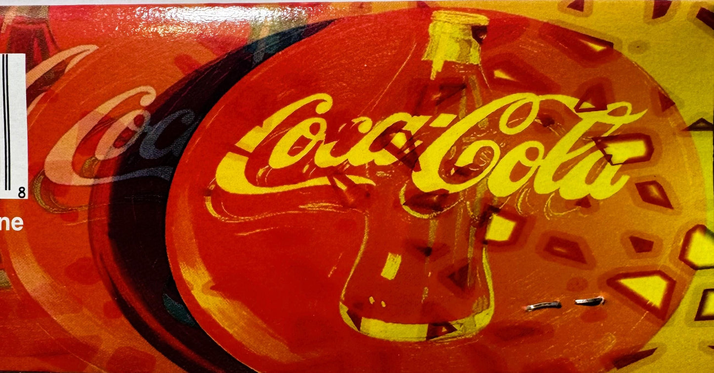 Close-up of red and yellow Coca-Cola disc showing curved yellow script logo on glossy red surface with black curved stripe de