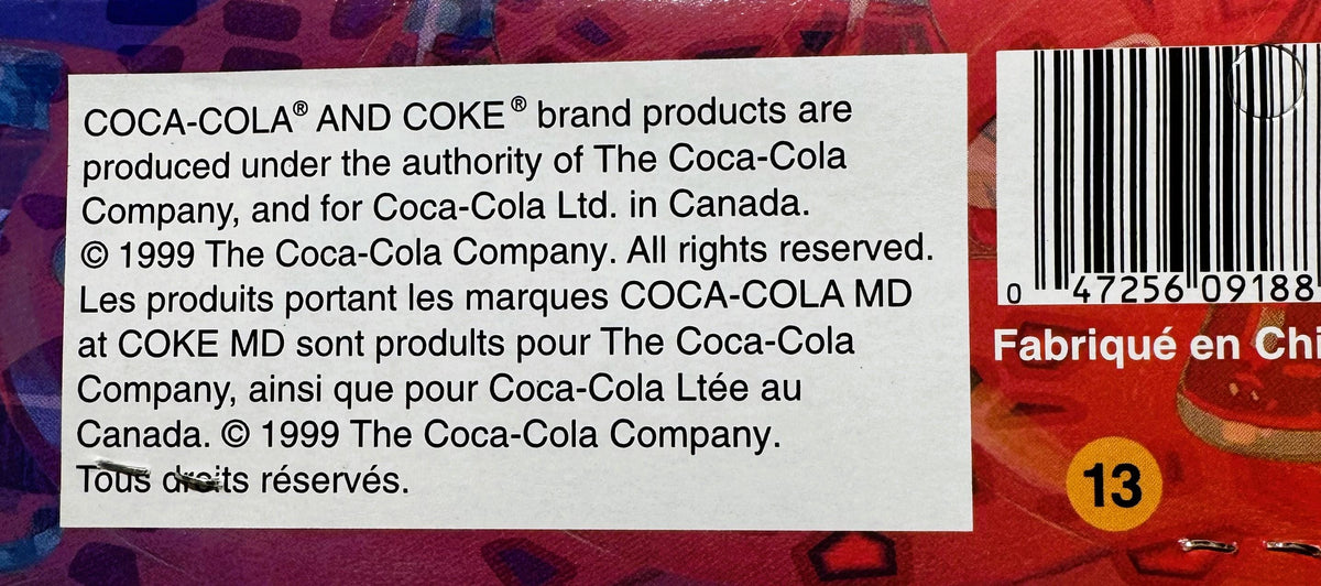 Close-up of copyright and legal text on red Coca-Cola packaging from 1999, with barcode and yellow number 13 visible on right
