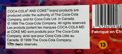 Close-up of copyright and legal text on red Coca-Cola packaging from 1999, with barcode and yellow number 13 visible on right