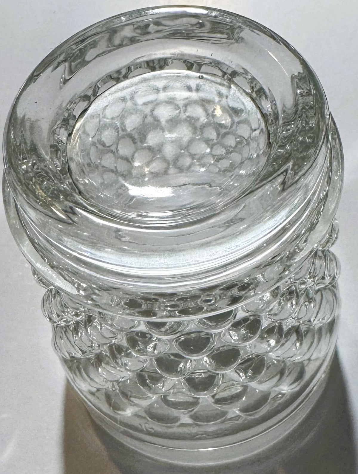 Clear glass hobnail tumbler photographed from above showing textured bubble pattern on lower half and smooth rim, viewed agai