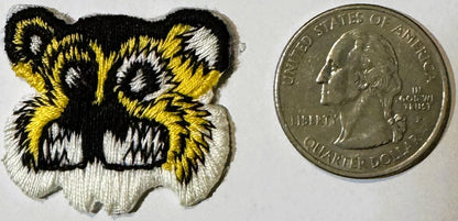 Vintage embroidered tiger face patch with yellow, black, and white thread next to a US quarter for scale.