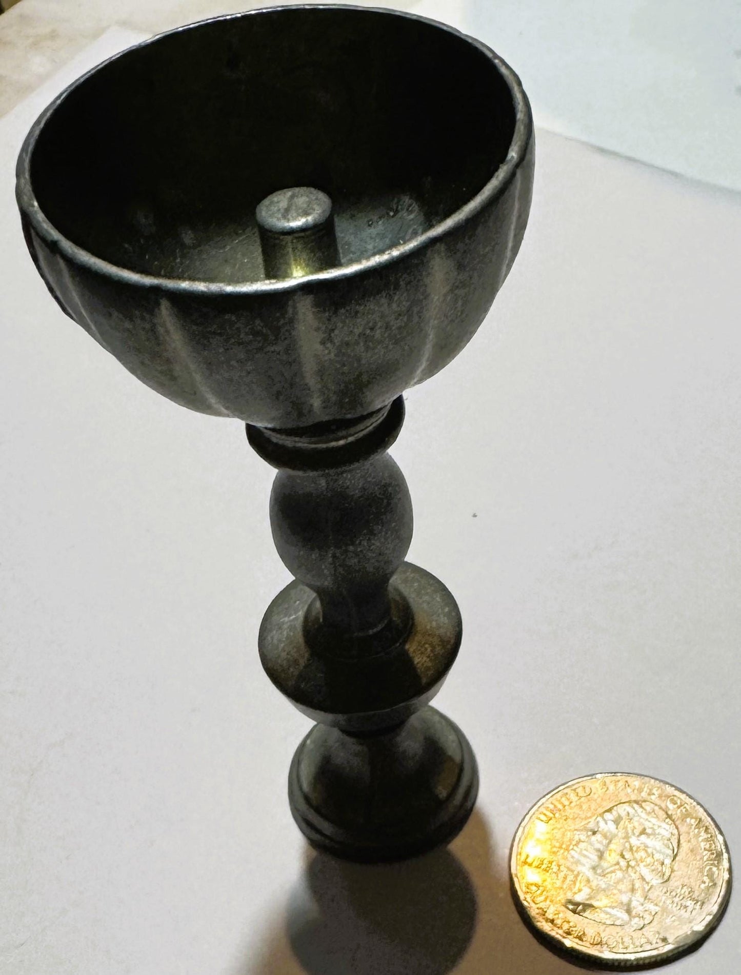 Vintage pewter miniature goblet with fluted bowl and baluster stem next to a British pound coin for scale