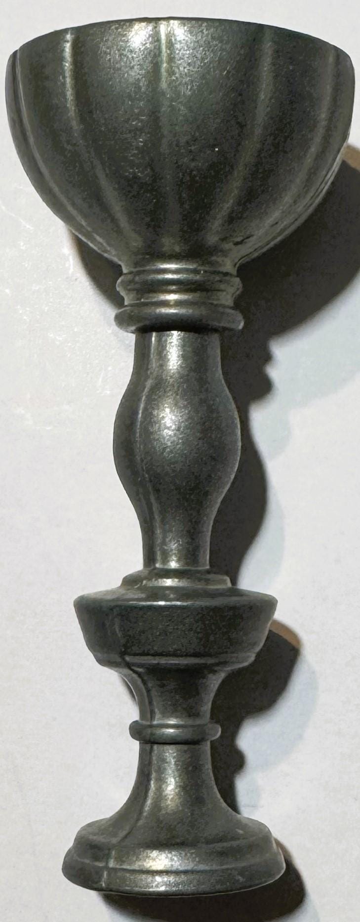 Vintage pewter goblet with fluted bowl and baluster stem, shown against white background with shadow cast to the right