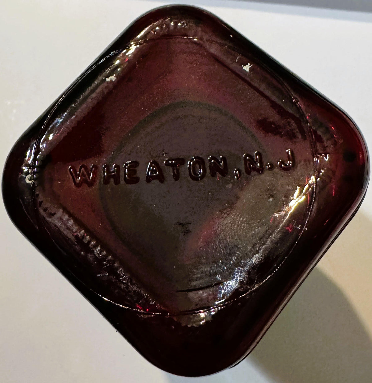 Overhead view of the square glass base with WHEATON, N.J. embossed in raised letters.