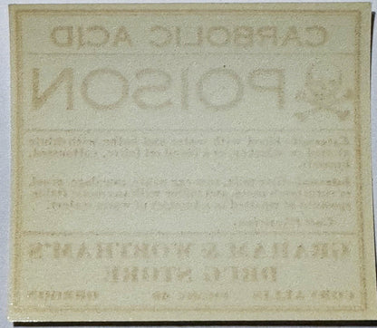 Cream-colored antique poison label with embossed text reading "CARBOLIC ACID" and "Graham & Worthams Drug Store, Corvallis OR