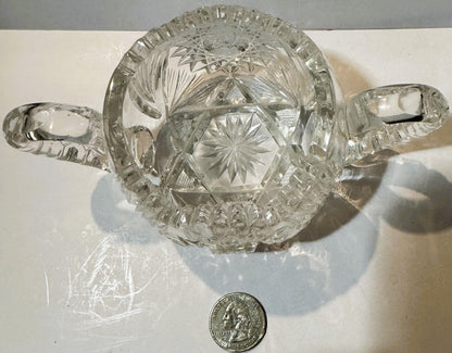 Antique cut glass two-handled sugar bowl with star and geometric patterns, shown from above with a quarter coin for scale