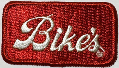 Red sequined patch with white embroidered script reading "Bike's" against a light background