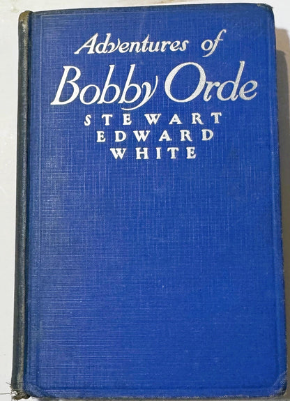 Blue cloth hardcover book with white serif title text reading "Adventures of Bobby Orde" and author "Stewart Edward White