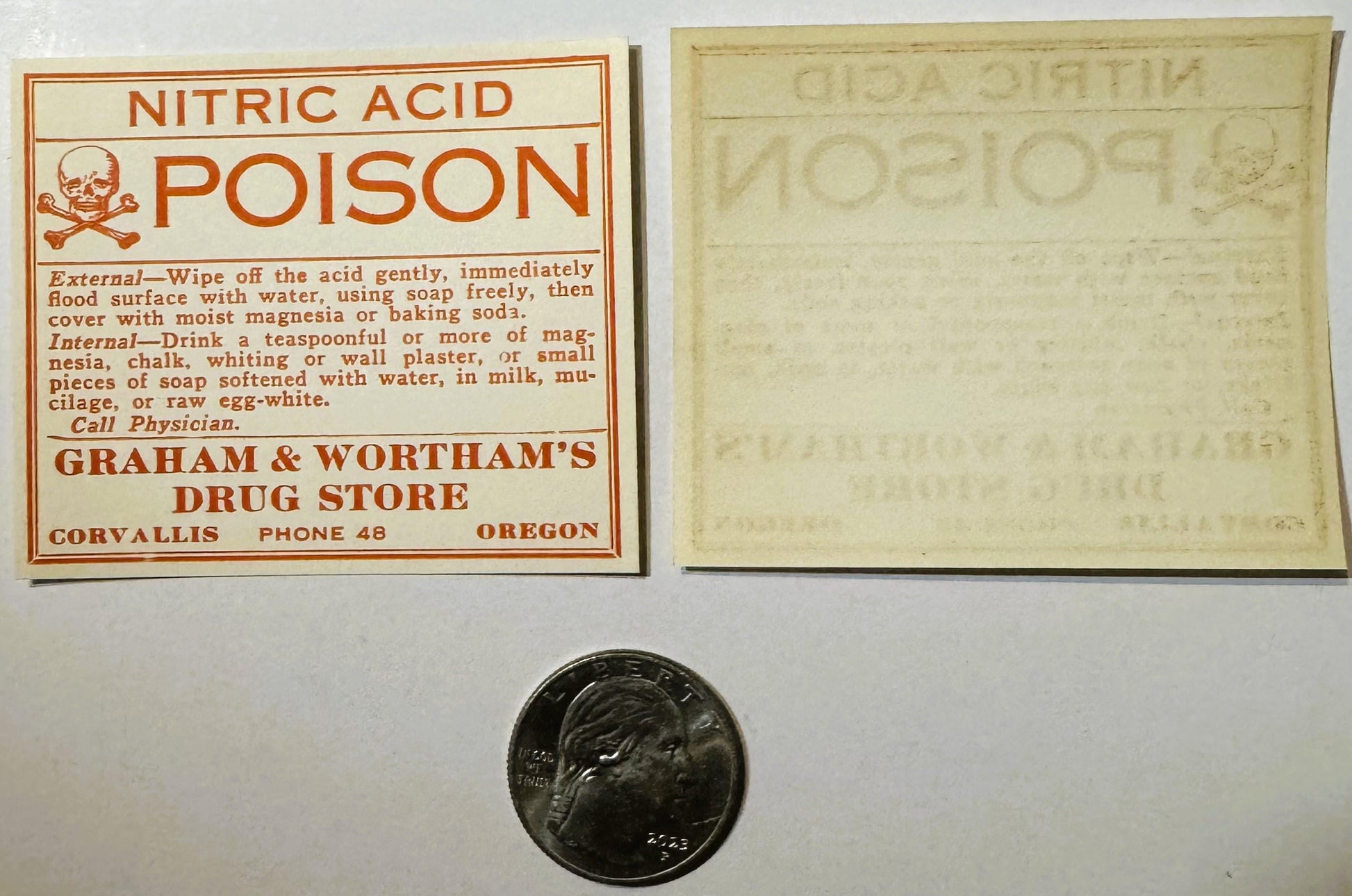 Vintage nitric acid poison label with skull and crossbones, treatment instructions, and drug store details, displayed with ba