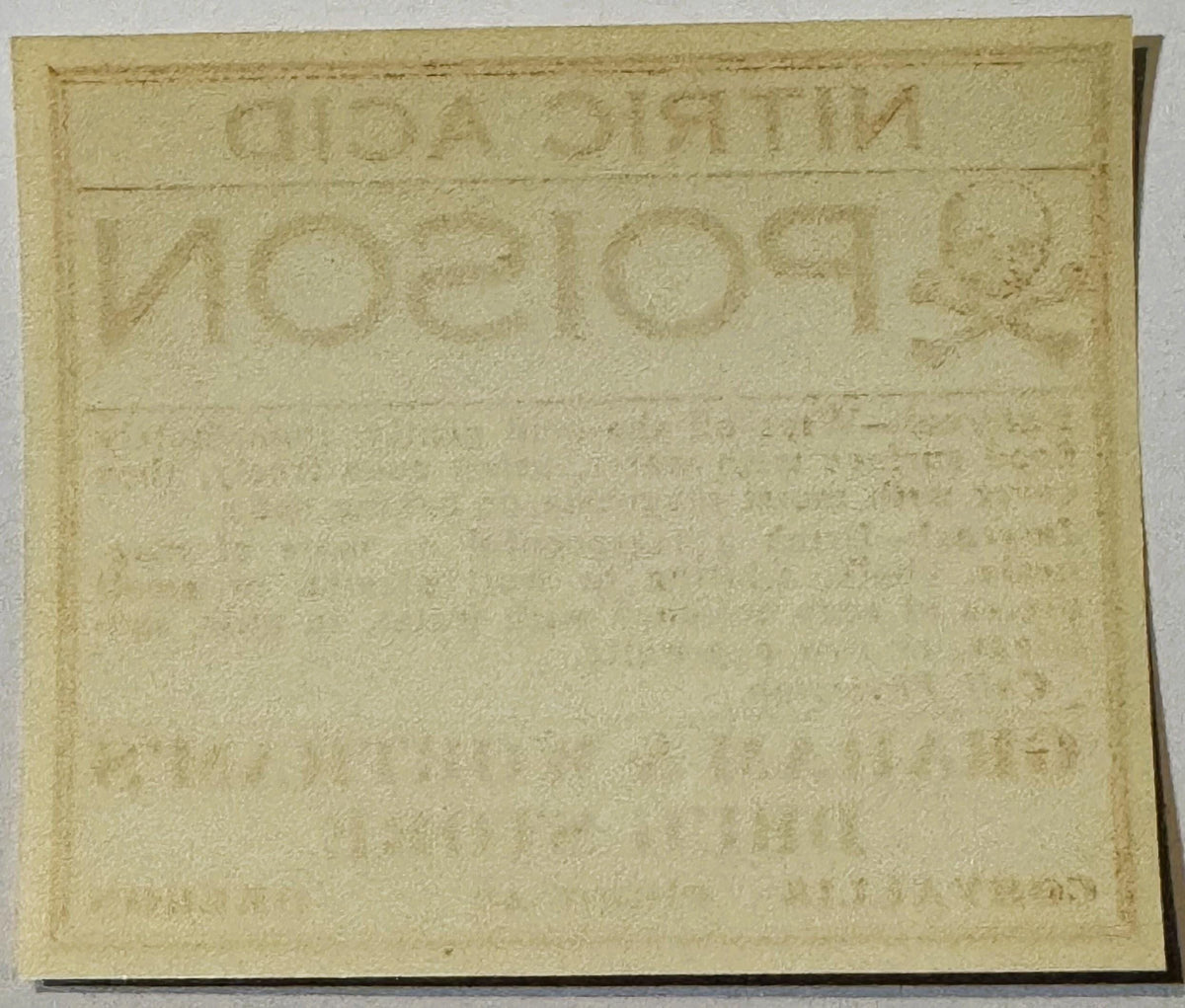 Cream-colored antique poison label with embossed text, photographed flat against white background showing wear and age patina