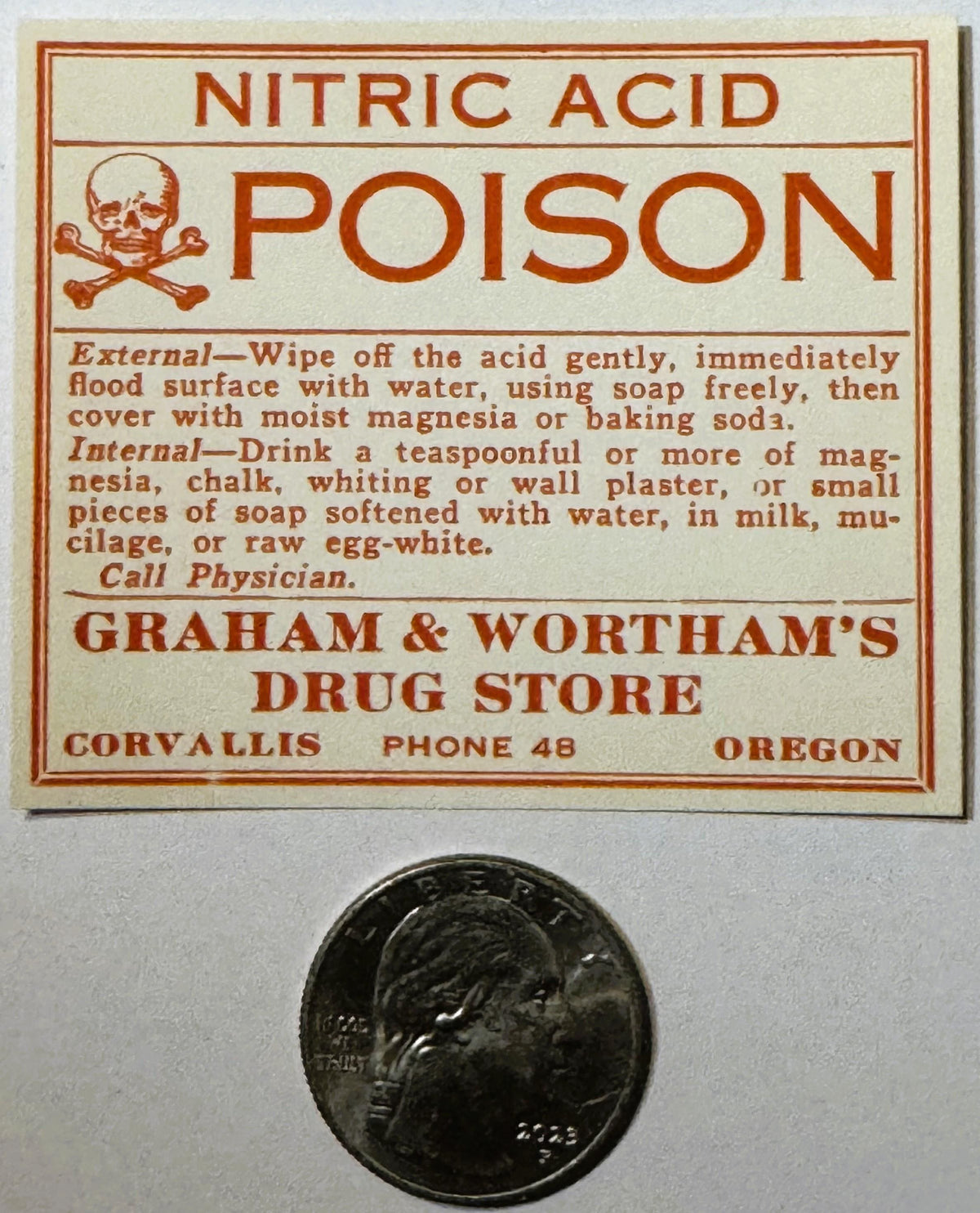 Vintage nitric acid poison label with skull and crossbones, treatment instructions, and drug store details, shown next to a q