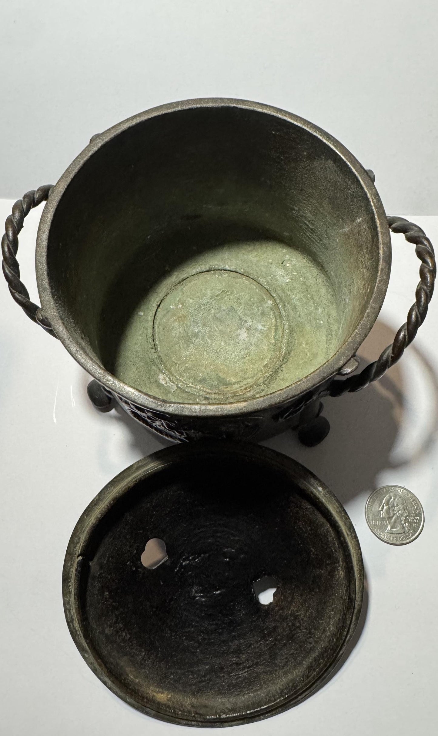 Overhead view of bronze censer with twisted handles, removable lid showing patina, and quarter coin for scale
