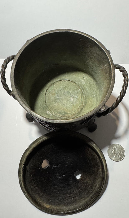 Overhead view of bronze censer with twisted handles, removable lid showing patina, and quarter coin for scale