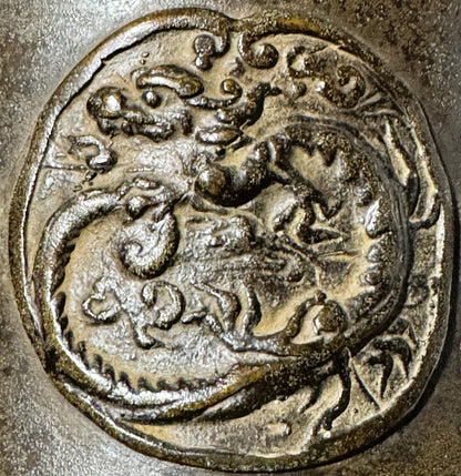 Close-up detail of ornate bronze relief showing dragon and peach motif with patina and wear on beige textured surface