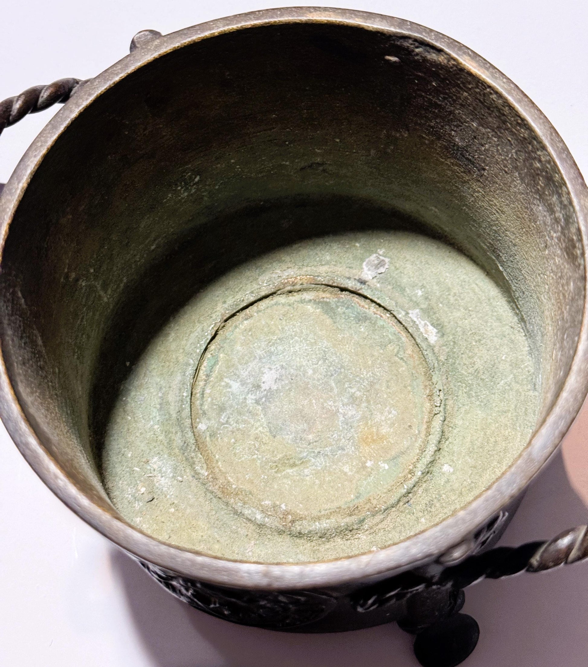 Interior overhead view of antique bronze censer showing patina-covered base with concentric circular markings and dark oxidiz