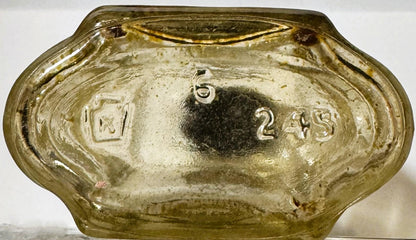 Bottom of vintage pressed glass bottle with embossed numbers "5" and "2" visible on pale green glass against white background