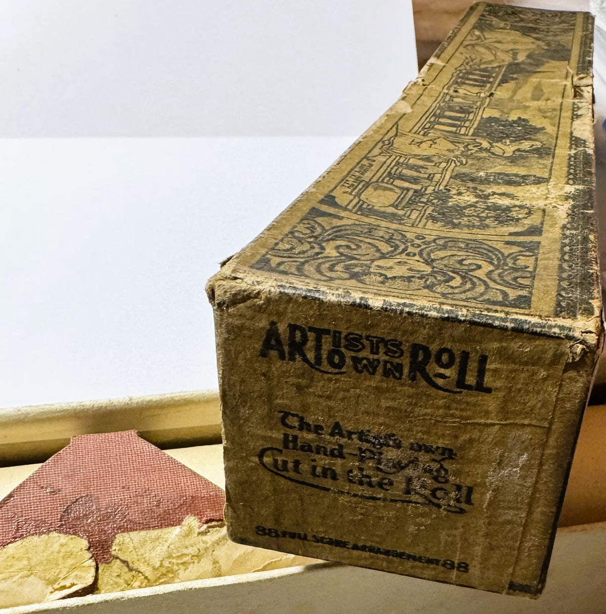 Aged cardboard box for Artists Roll player piano roll with decorative illustrated top, printed text visible on side